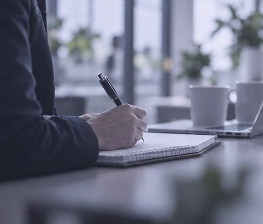 Hand macht Notizen am Schreibtisch